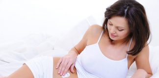 Femme enceinte s'appliquant de la crème anti vergetures sur le ventre.