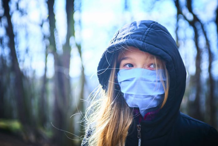 Une jeune femme à l'air déprimé sous son masque, en plein hiver, au moment du blue monday.