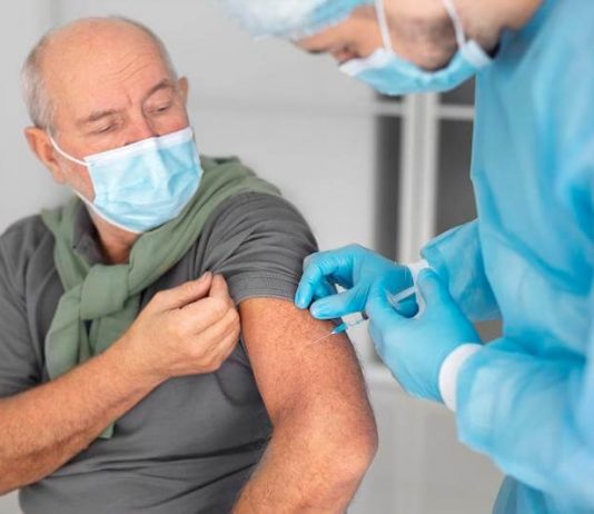 Un homme âgé reçoit la double vaccination grippe et covid-19.