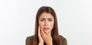 Une jeune femme souffrant des dents : parodontite ou carie.