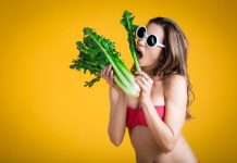 Une jeune femme faisant semblant de manger des légumes pour perdre des kilos avant le retour à la plage.